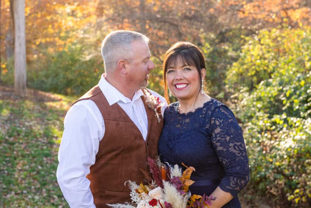 Happy couple after getting married in Nashville. Groom is wearing a brown leather vest and white shirt, and the bride is wearing a navy lace dress.