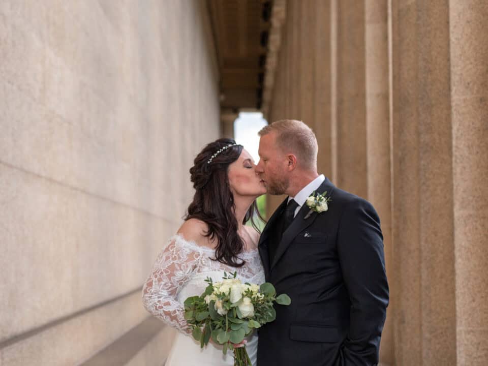 Bride and groom kiss under the shelter of the Parthenon, a great option for a free elopement location