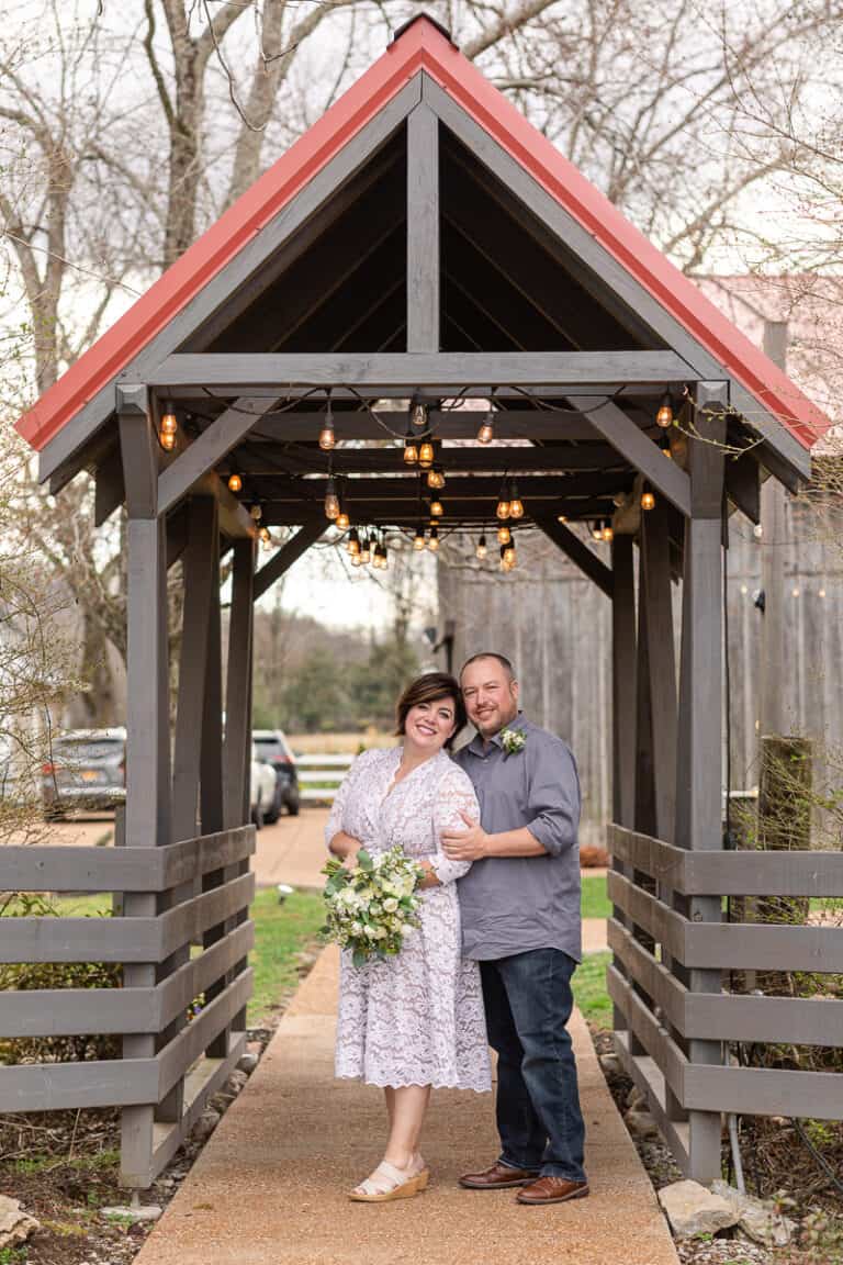 bride and groom pose under small covered walkway