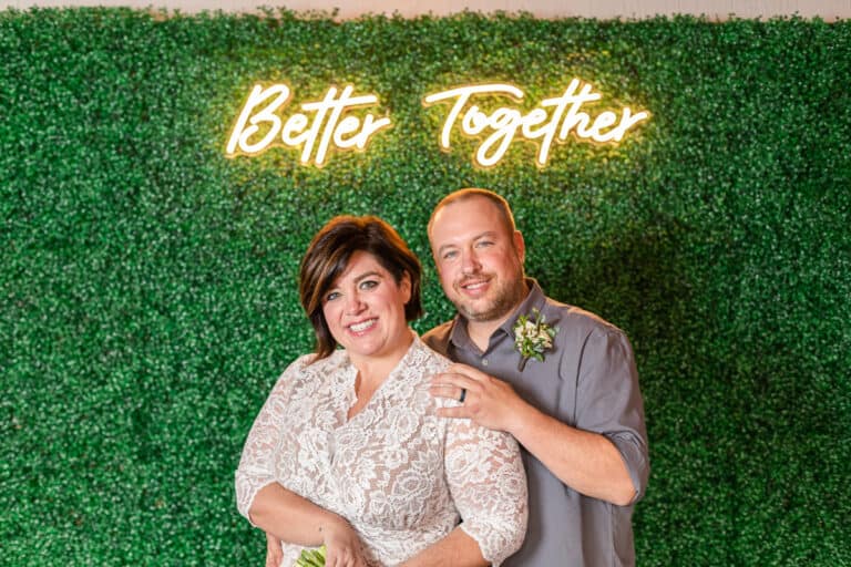 couple pose under neon sign saying Better Together