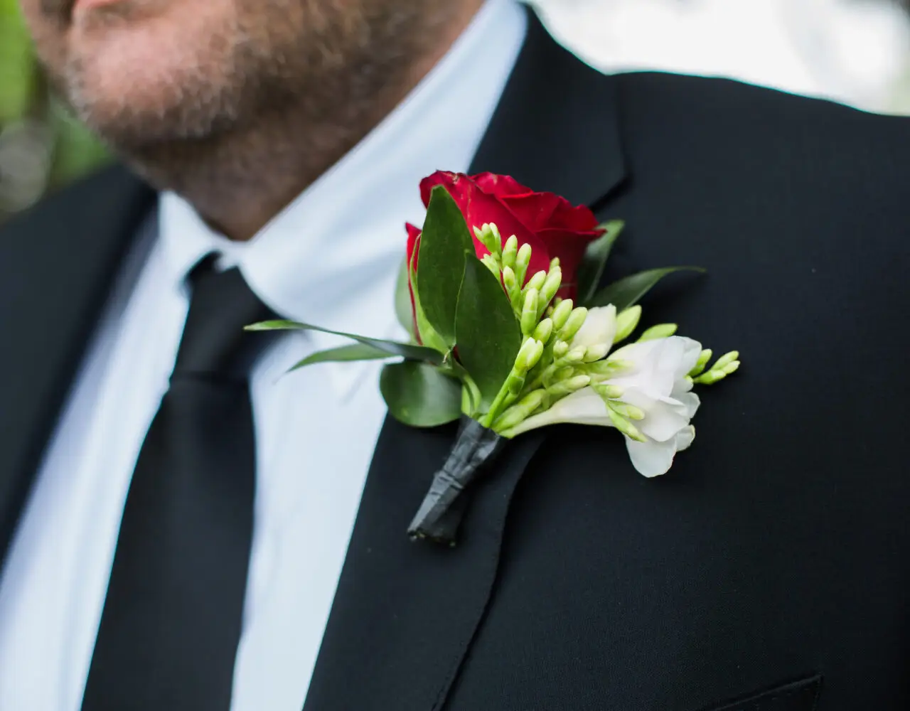 red rose bountonniere on black men's suit