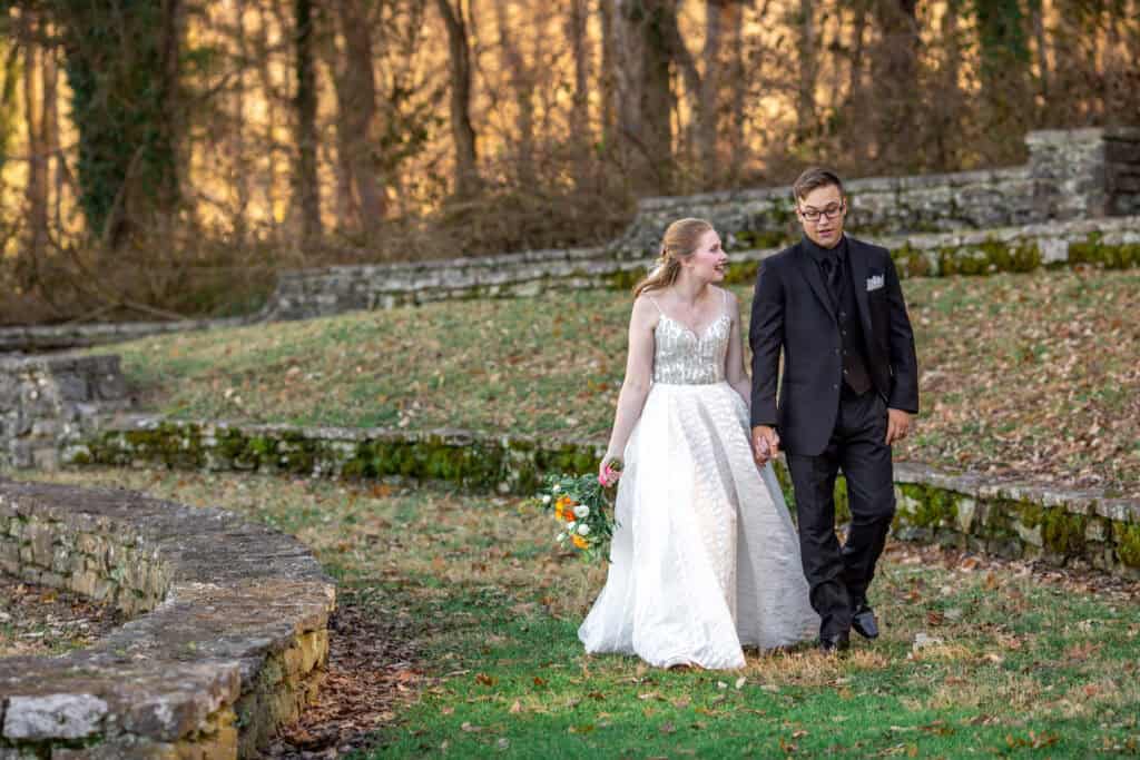 elopement portrait of bride and groom walking in park at golden hour.